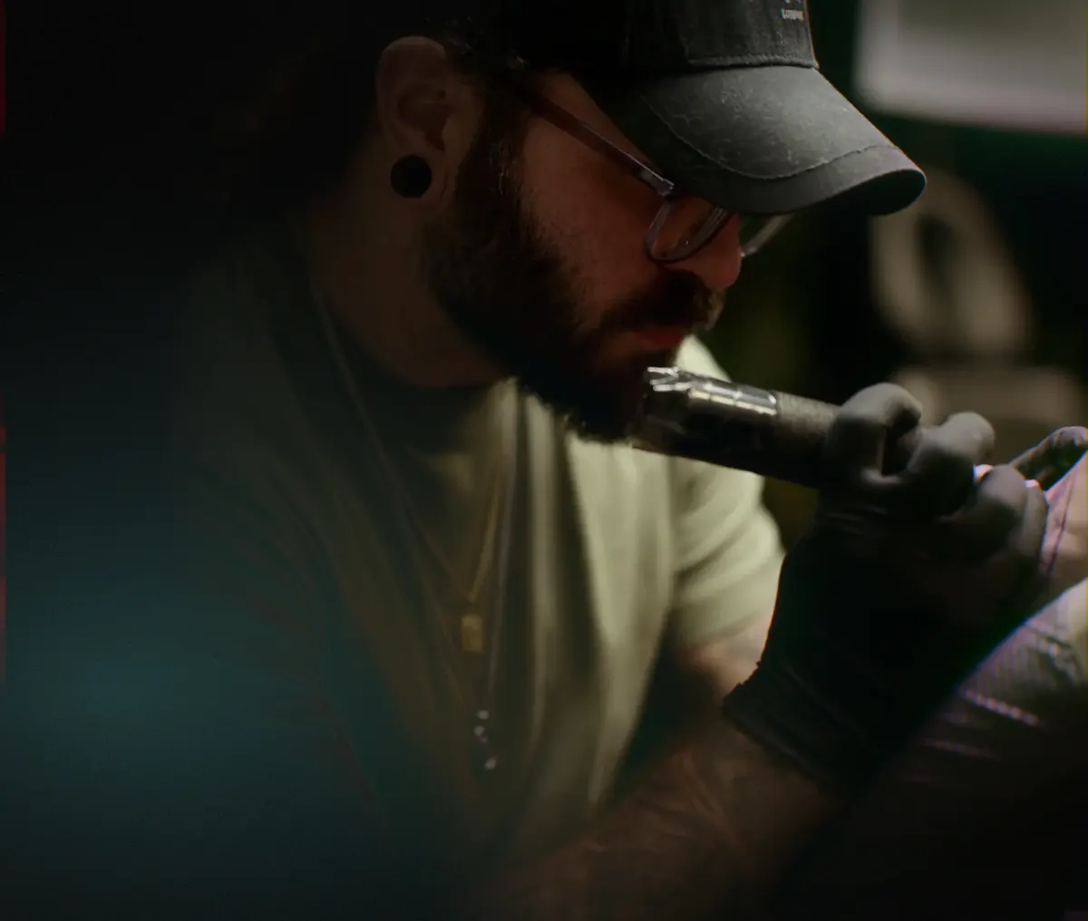 Bobby Cupparo tattooing a client in his Austin, Texas studio — close-up portrait showing focused technique with tattoo machine