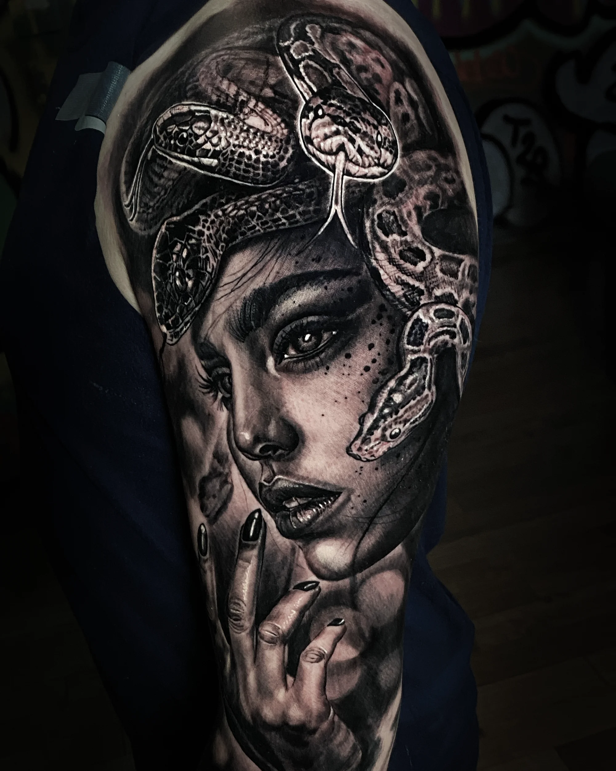 Black and grey Medusa snake portrait upper arm tattoo by Austin tattoo artist Bobby Cupparo