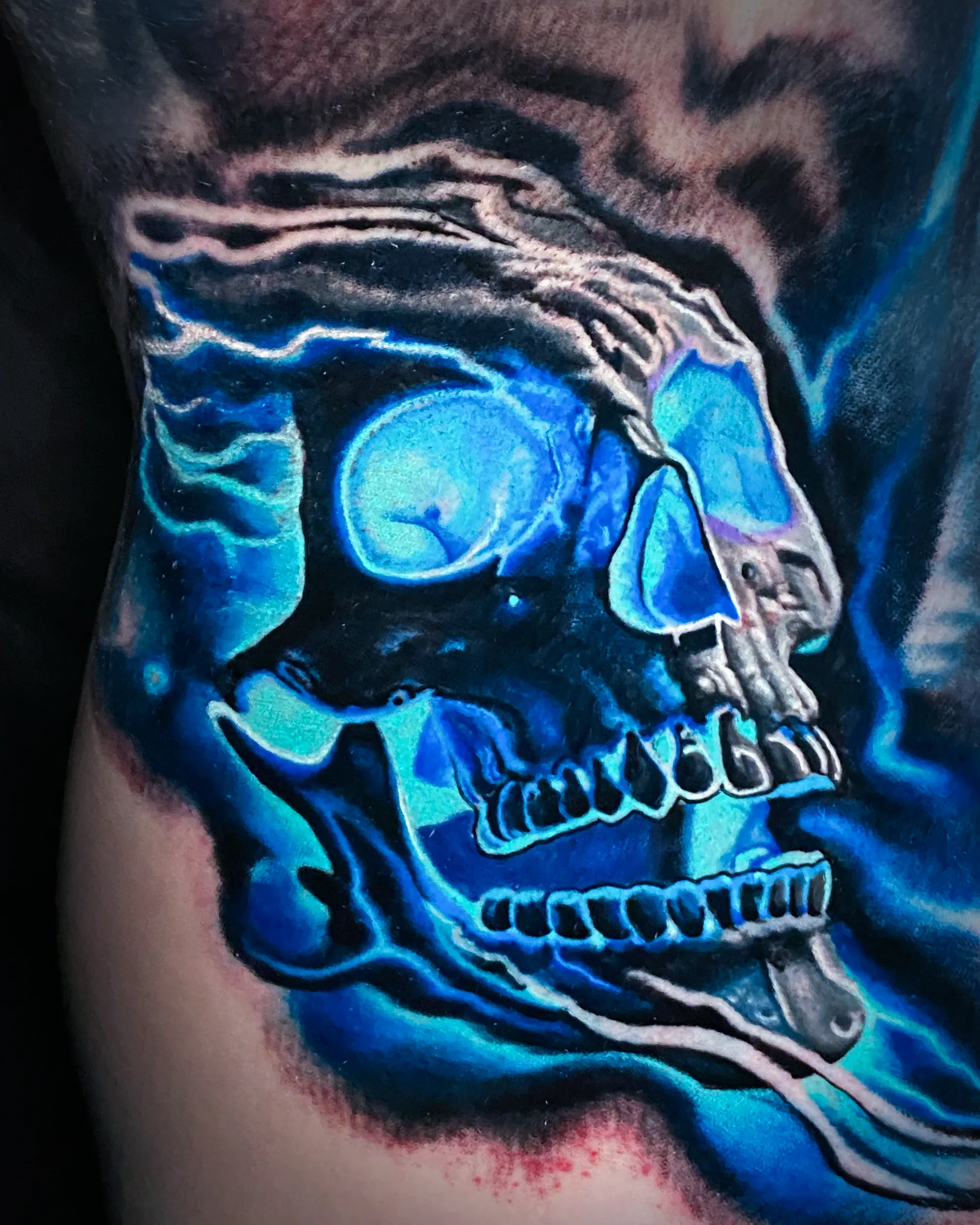 Color realism blue flaming skull upper arm tattoo by Austin tattoo artist Bobby Cupparo