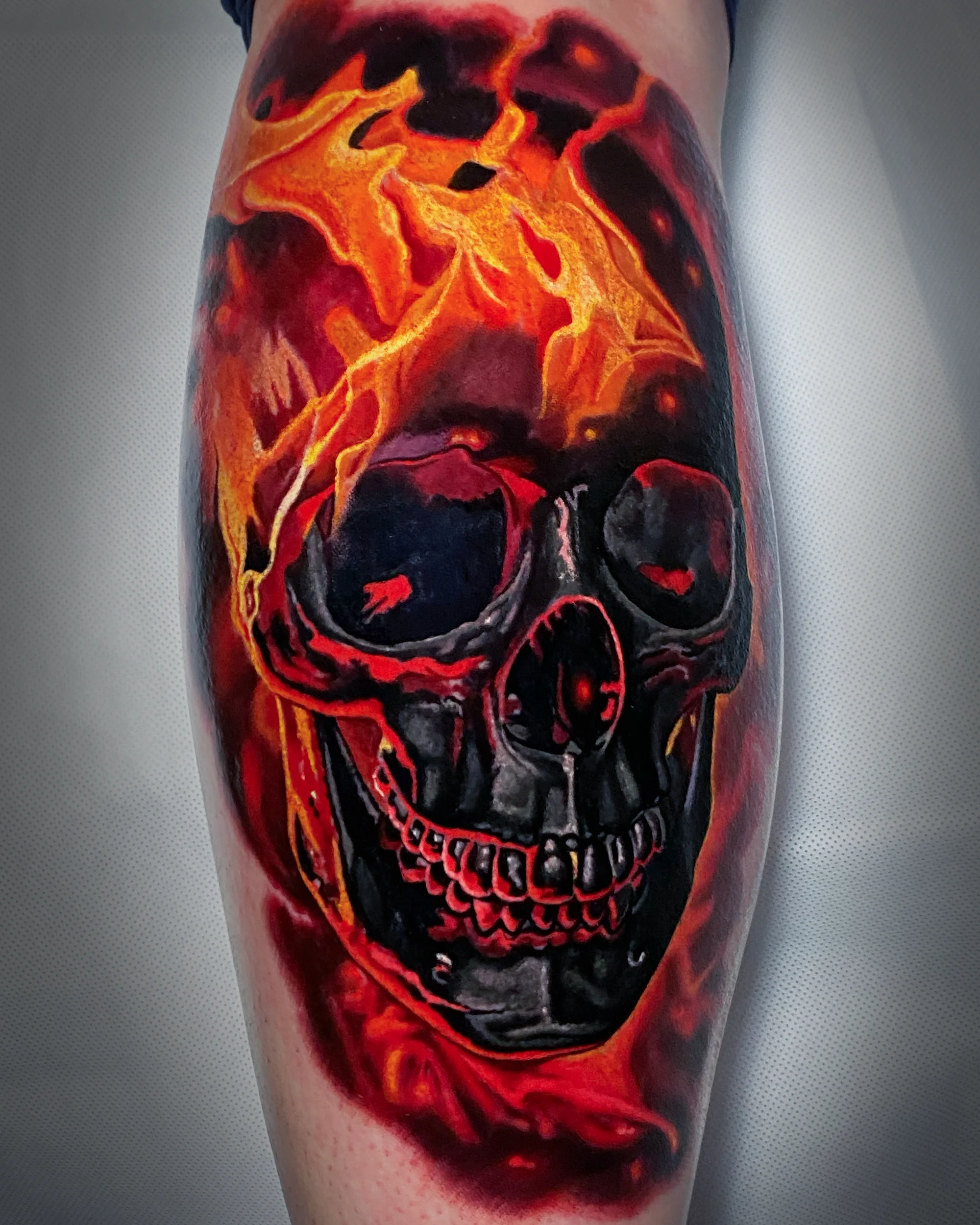 Color realism flaming skull red orange thigh tattoo by Austin tattoo artist Bobby Cupparo