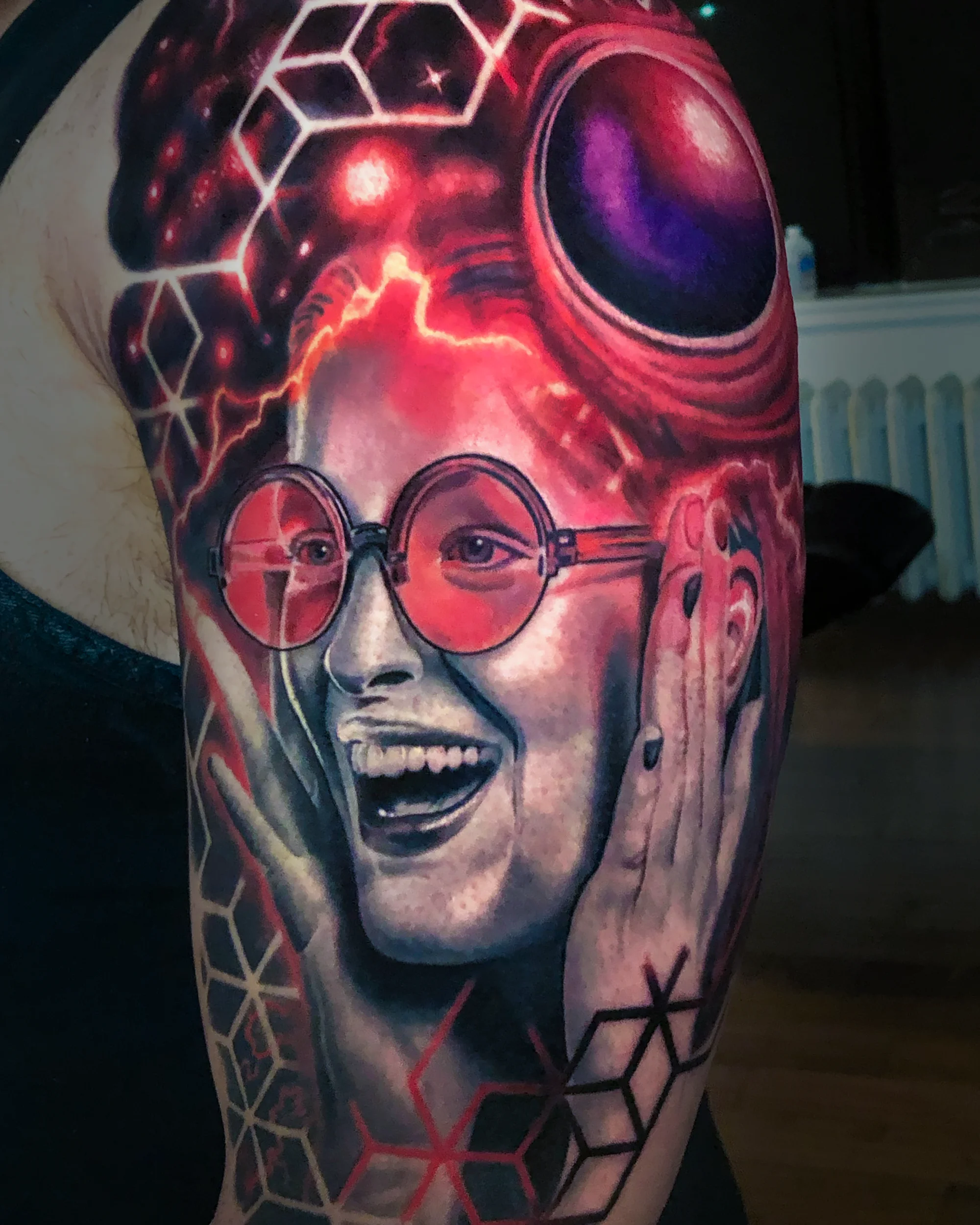 Color realism neon female portrait with red sunglasses forearm tattoo by Austin tattoo artist Bobby Cupparo