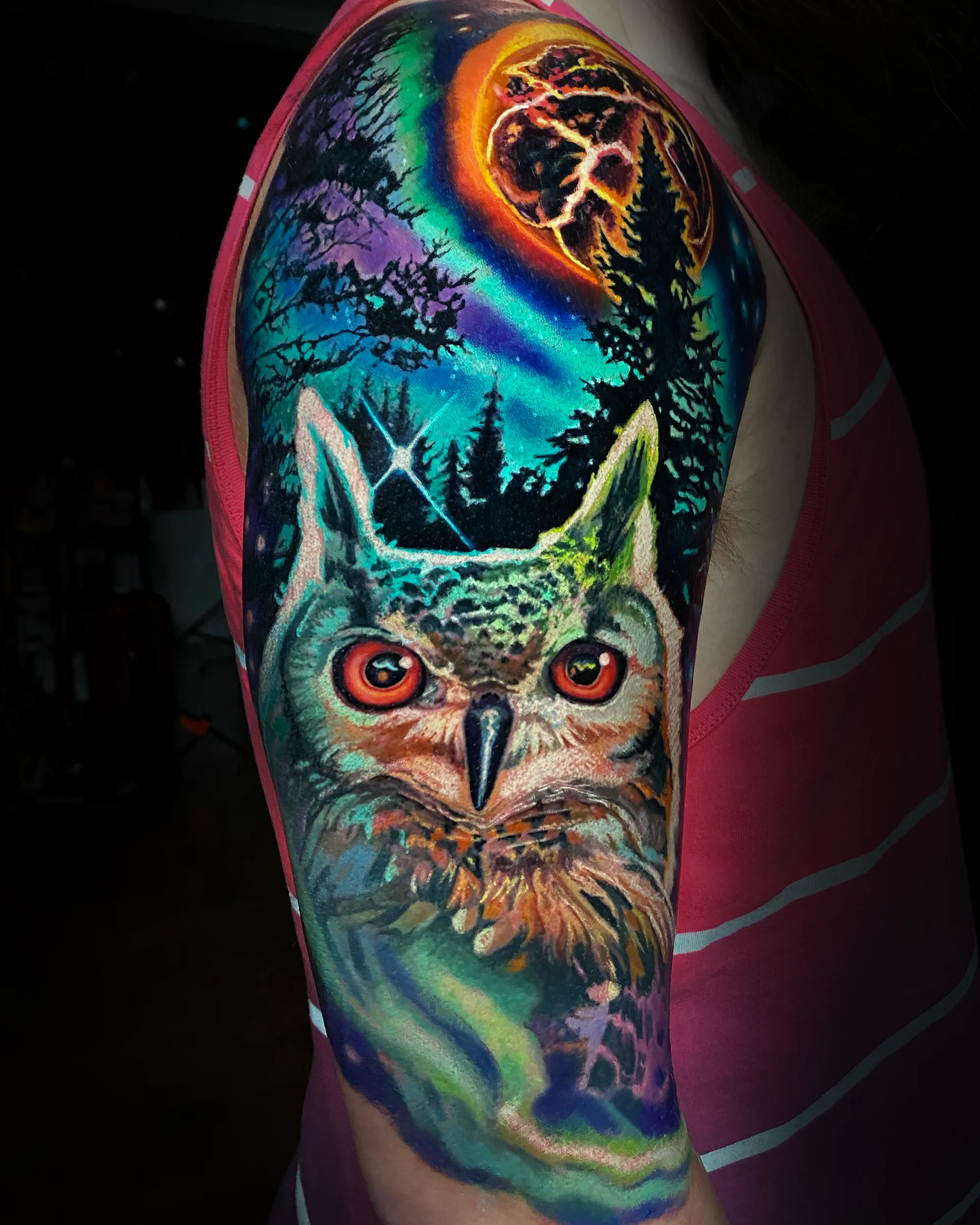 Color realism owl with aurora borealis and blood moon upper arm tattoo by Austin tattoo artist Bobby Cupparo