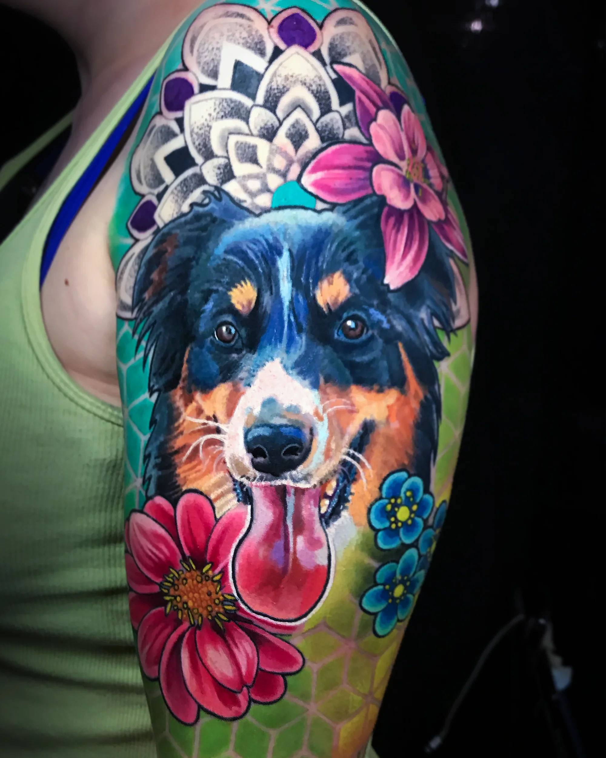 Color realism Australian Shepherd dog portrait with mandala and flowers upper arm tattoo by Austin tattoo artist Bobby Cupparo