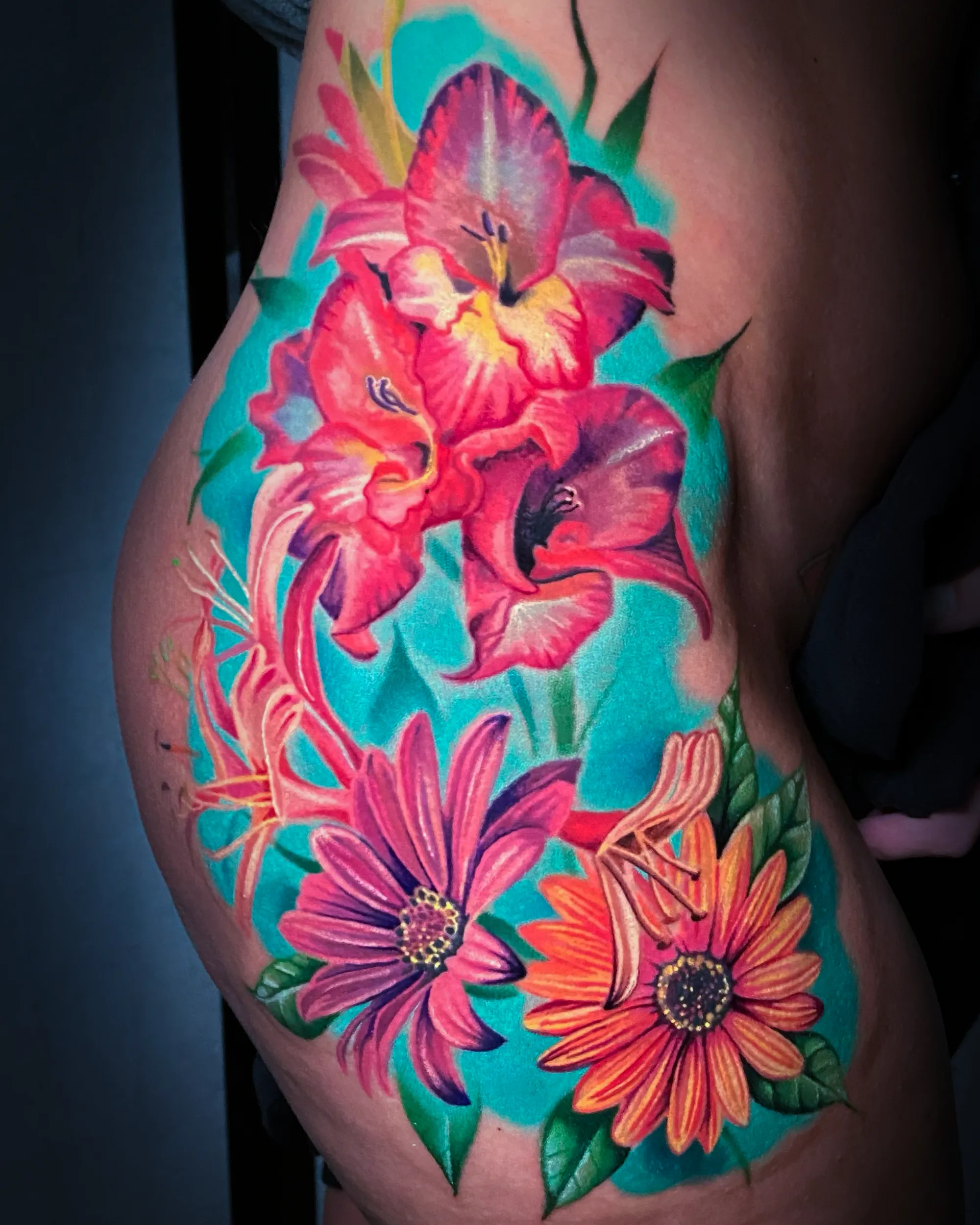 Color realism gladiolus and daisy botanical floral hip tattoo by Austin tattoo artist Bobby Cupparo
