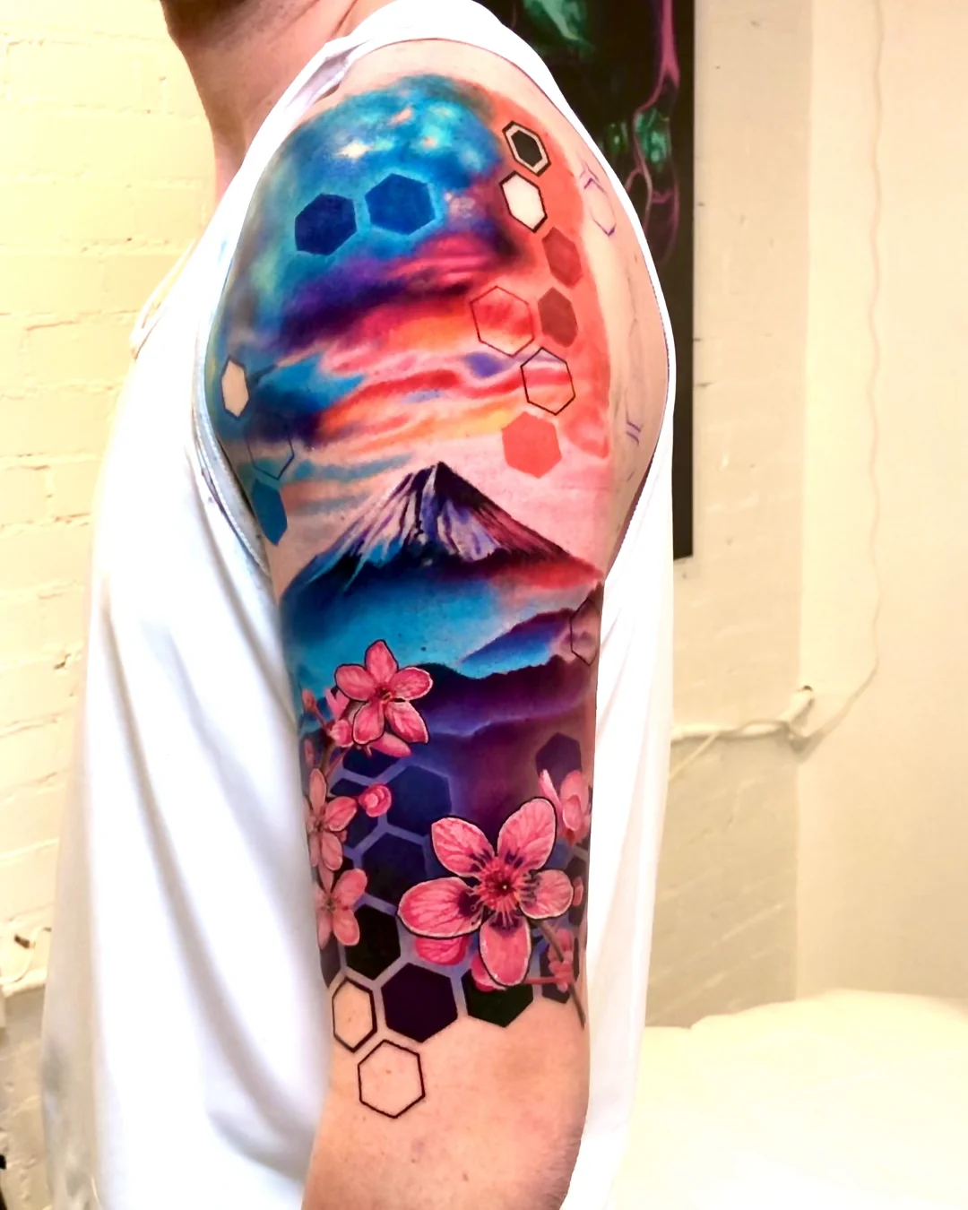 Color realism Mount Fuji at sunset with cherry blossoms and hexagons, upper arm and shoulder tattoo by Austin tattoo artist Bobby Cupparo