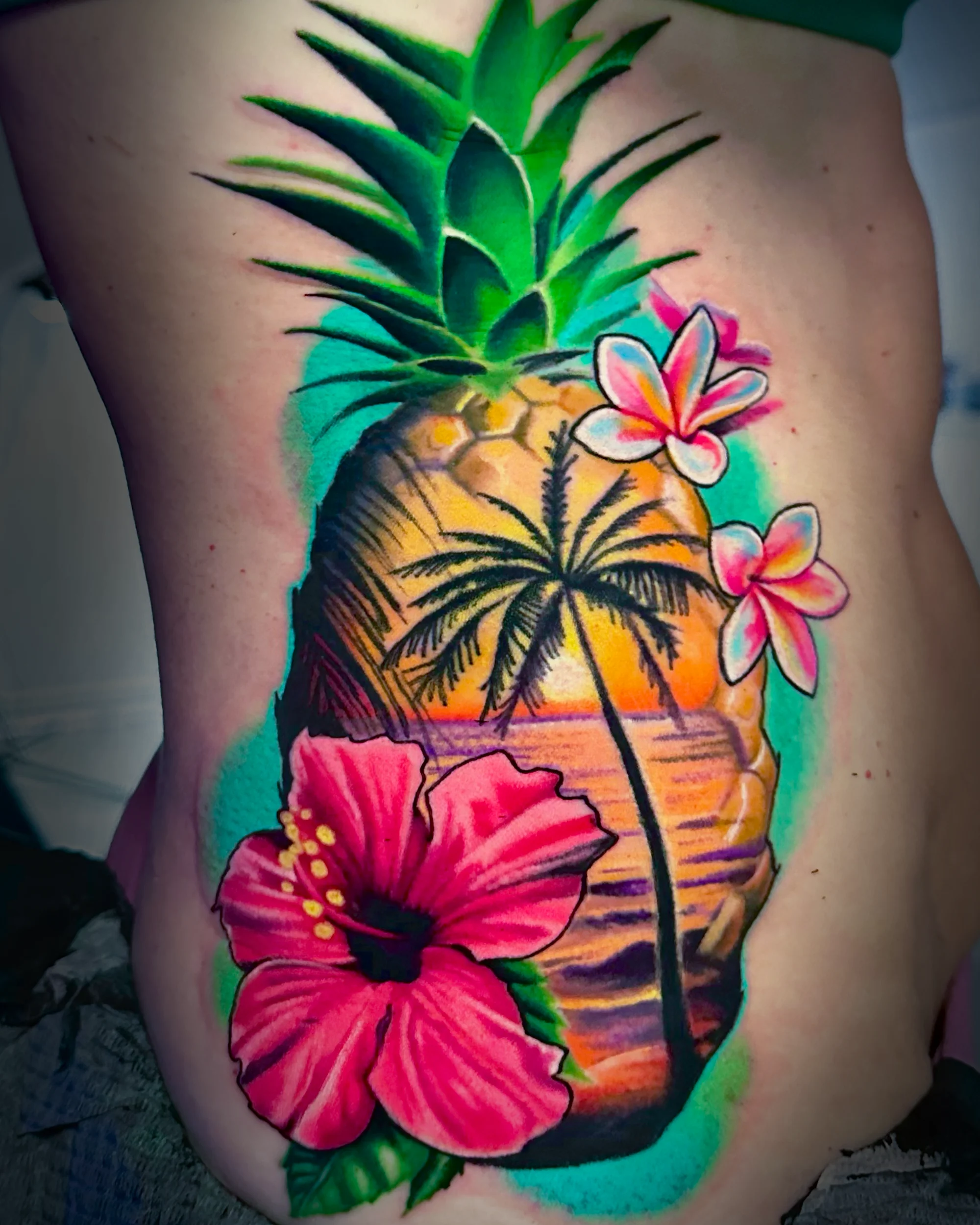 Color realism tropical pineapple hibiscus plumeria rib tattoo by Austin tattoo artist Bobby Cupparo