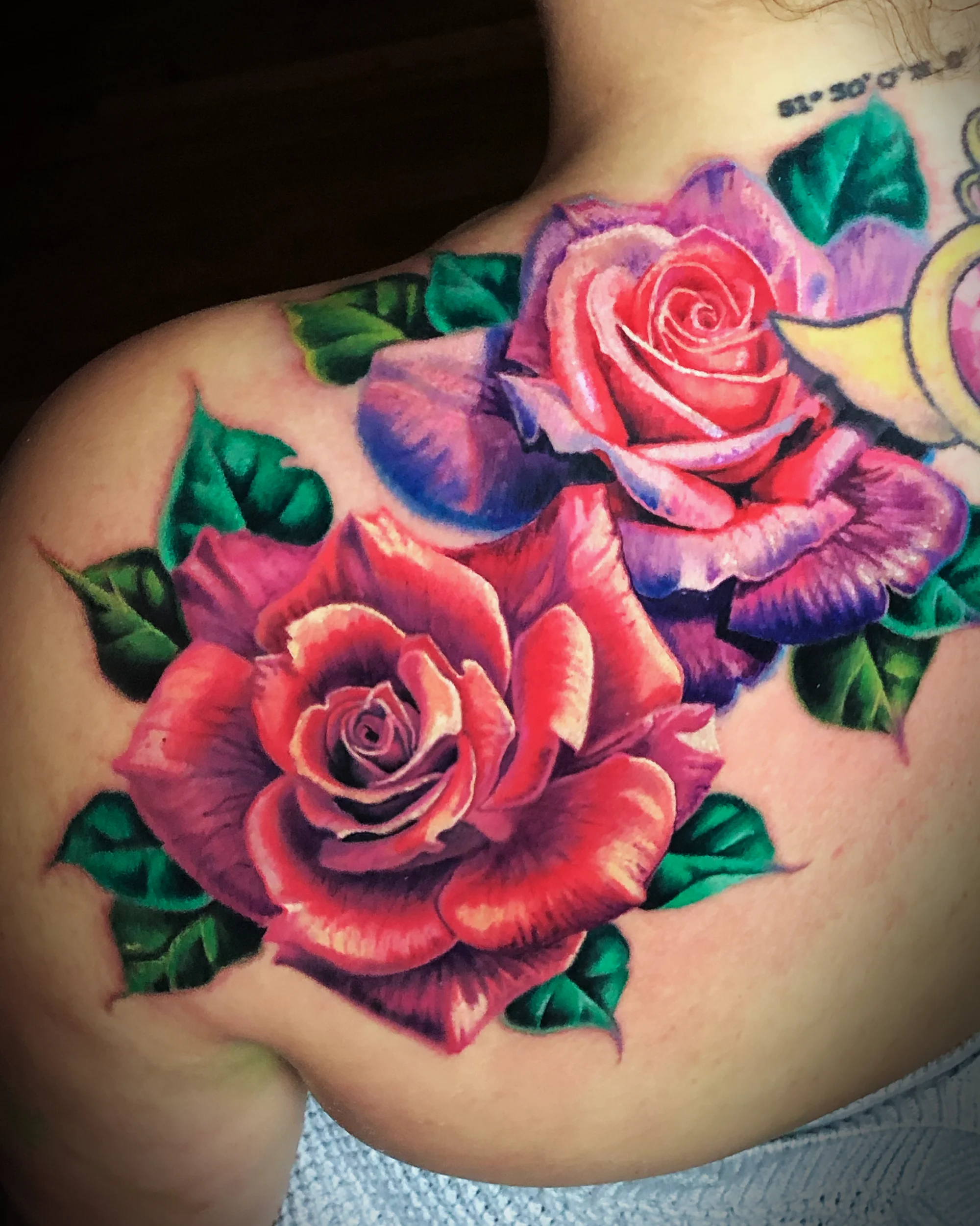Color realism red and purple roses shoulder blade tattoo by Austin tattoo artist Bobby Cupparo