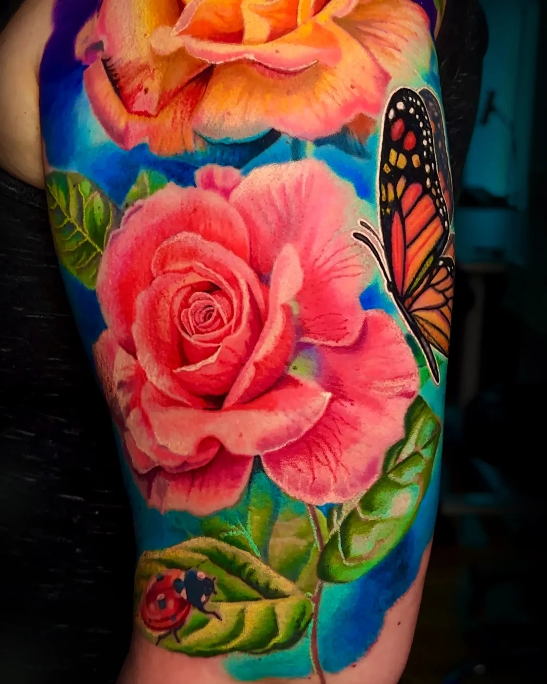 Color realism pink roses with monarch butterfly and ladybug upper arm tattoo by Austin tattoo artist Bobby Cupparo