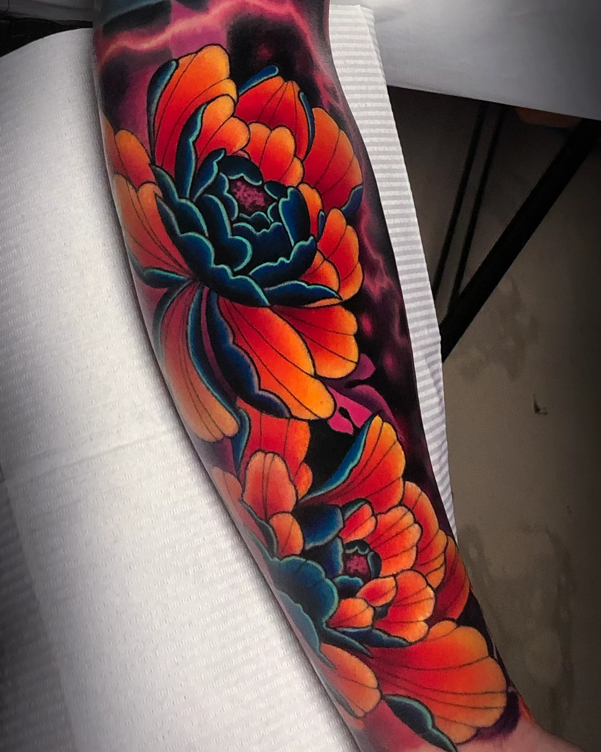 Neo-traditional vivid orange and teal peony forearm sleeve tattoo by Austin tattoo artist Bobby Cupparo