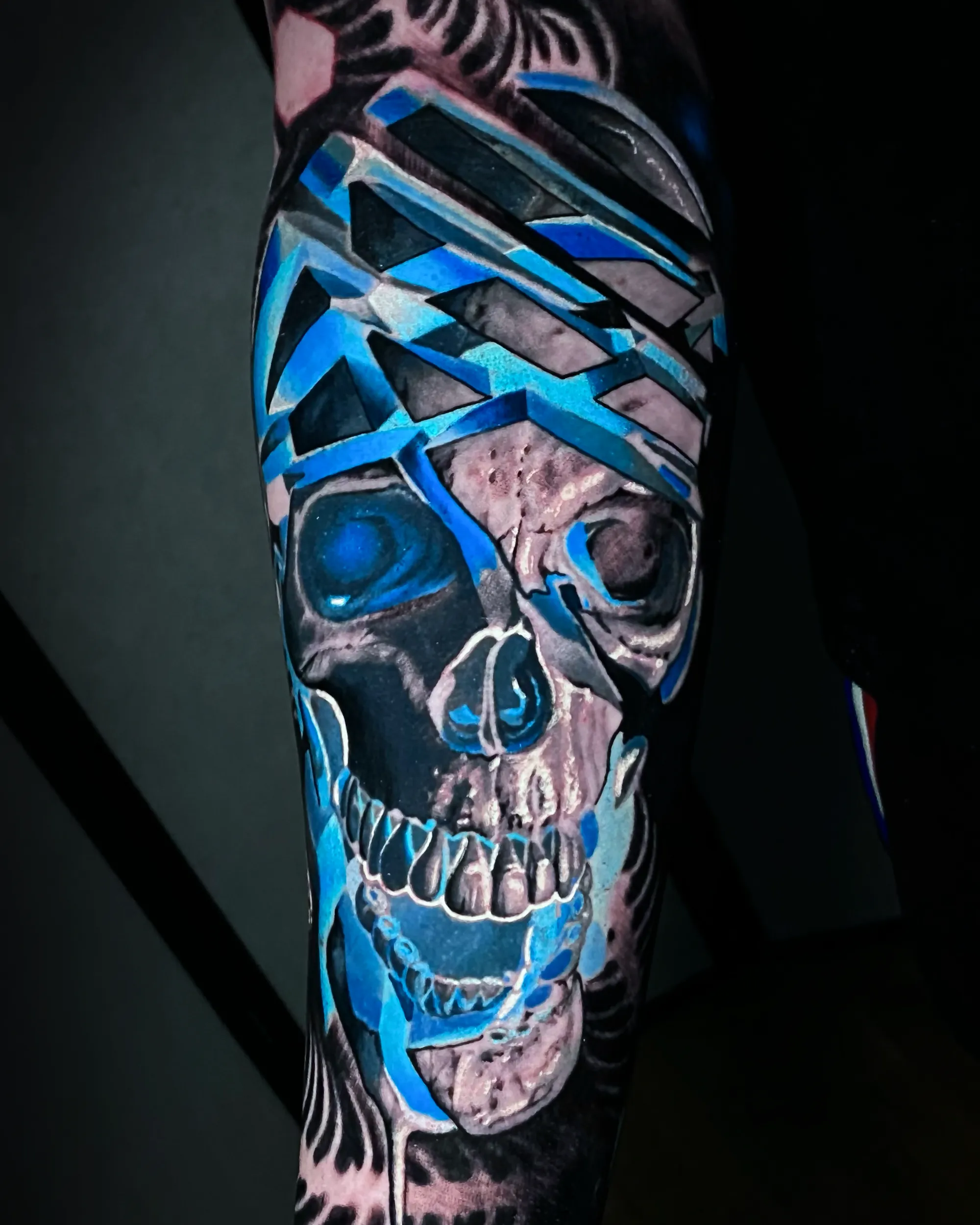 Surreal color blue geometric skull forearm sleeve tattoo by Austin tattoo artist Bobby Cupparo