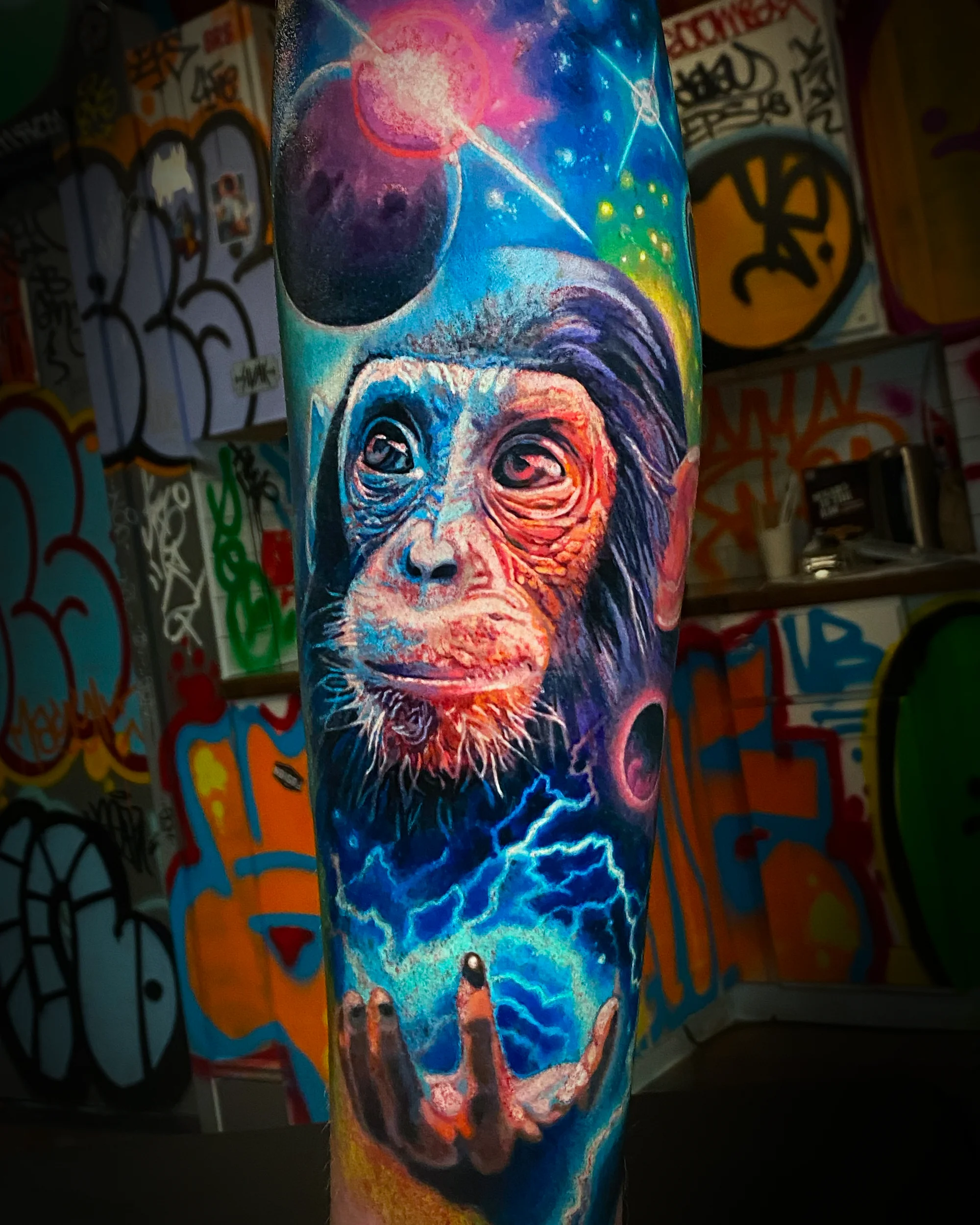 Surreal color cosmic chimpanzee with lightning forearm tattoo by Austin tattoo artist Bobby Cupparo