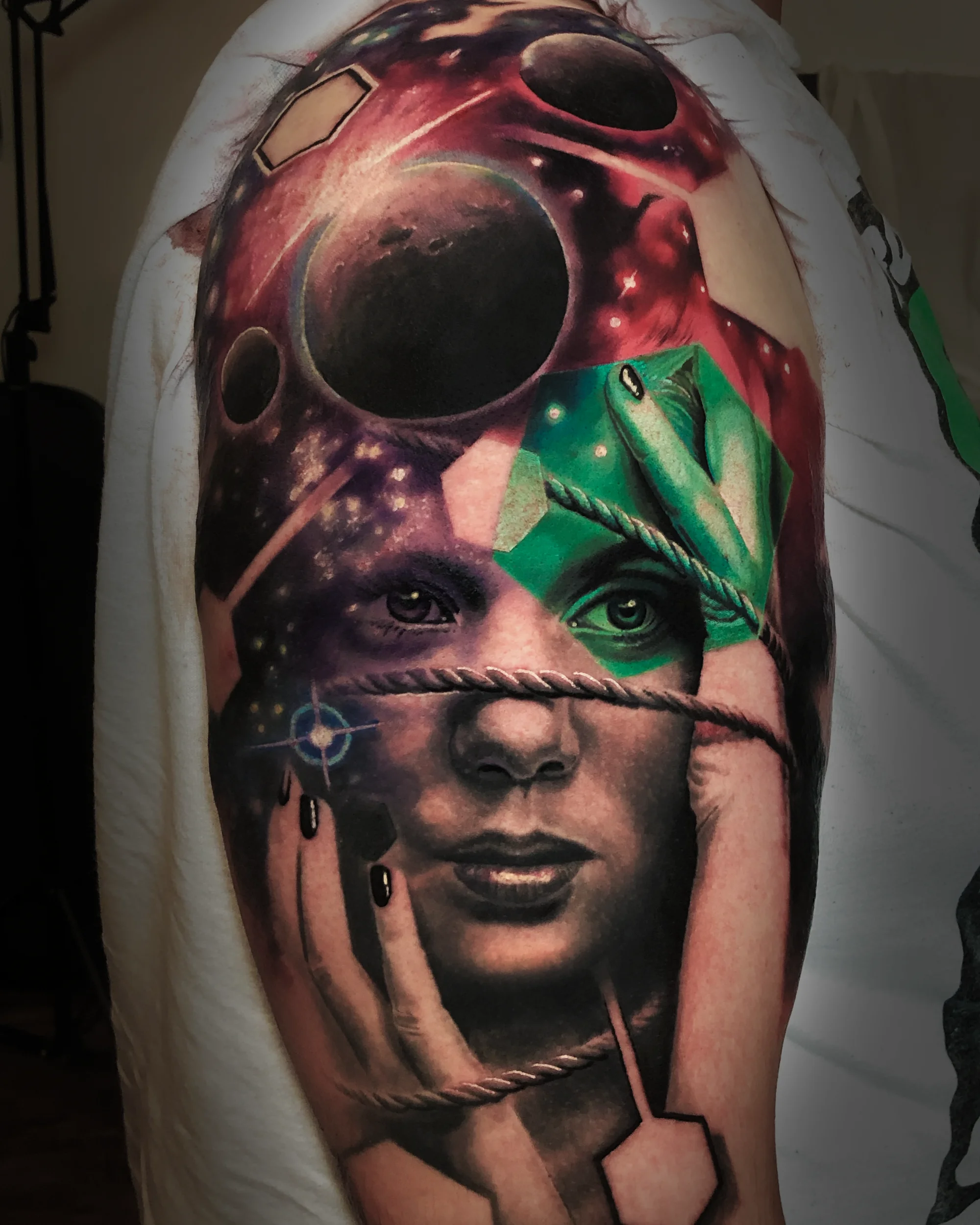 Surreal cosmic female portrait with planets and blindfold upper arm tattoo by Austin tattoo artist Bobby Cupparo