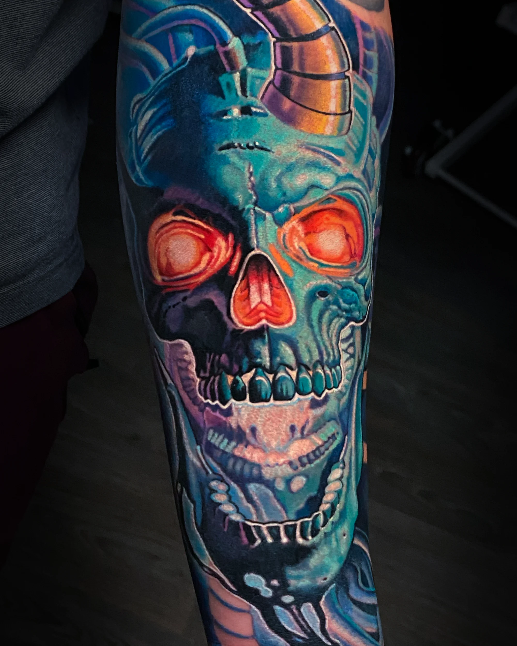 Surreal color cyberpunk horned skull teal forearm tattoo by Austin tattoo artist Bobby Cupparo