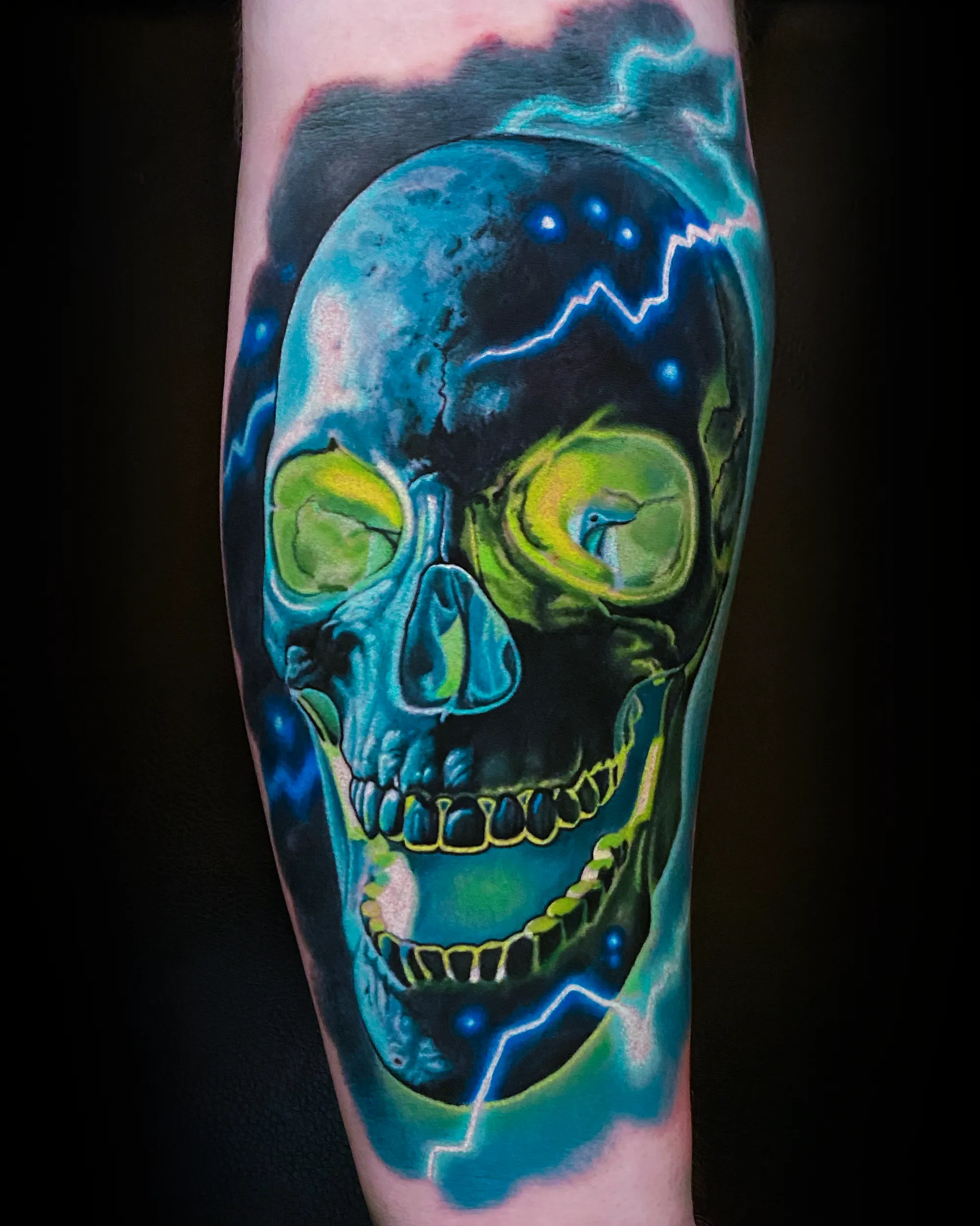 Color realism electric teal skull with green lightning forearm tattoo by Austin tattoo artist Bobby Cupparo