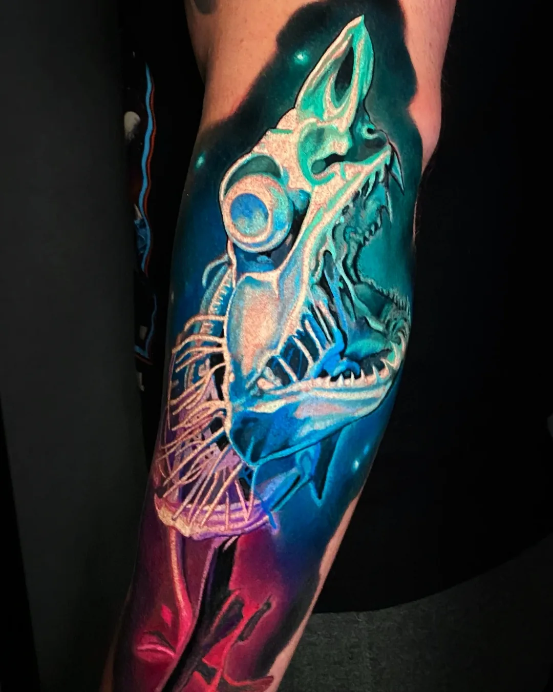 Surreal color neon bioluminescent fish skeleton forearm tattoo by Austin tattoo artist Bobby Cupparo