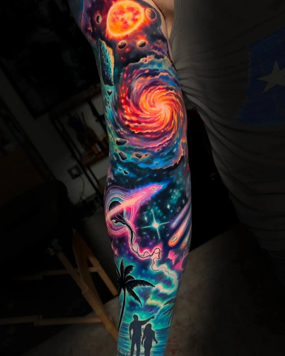 Surreal color galaxy nebula with spiral vortex planets and family silhouette full sleeve tattoo by Austin tattoo artist Bobby Cupparo