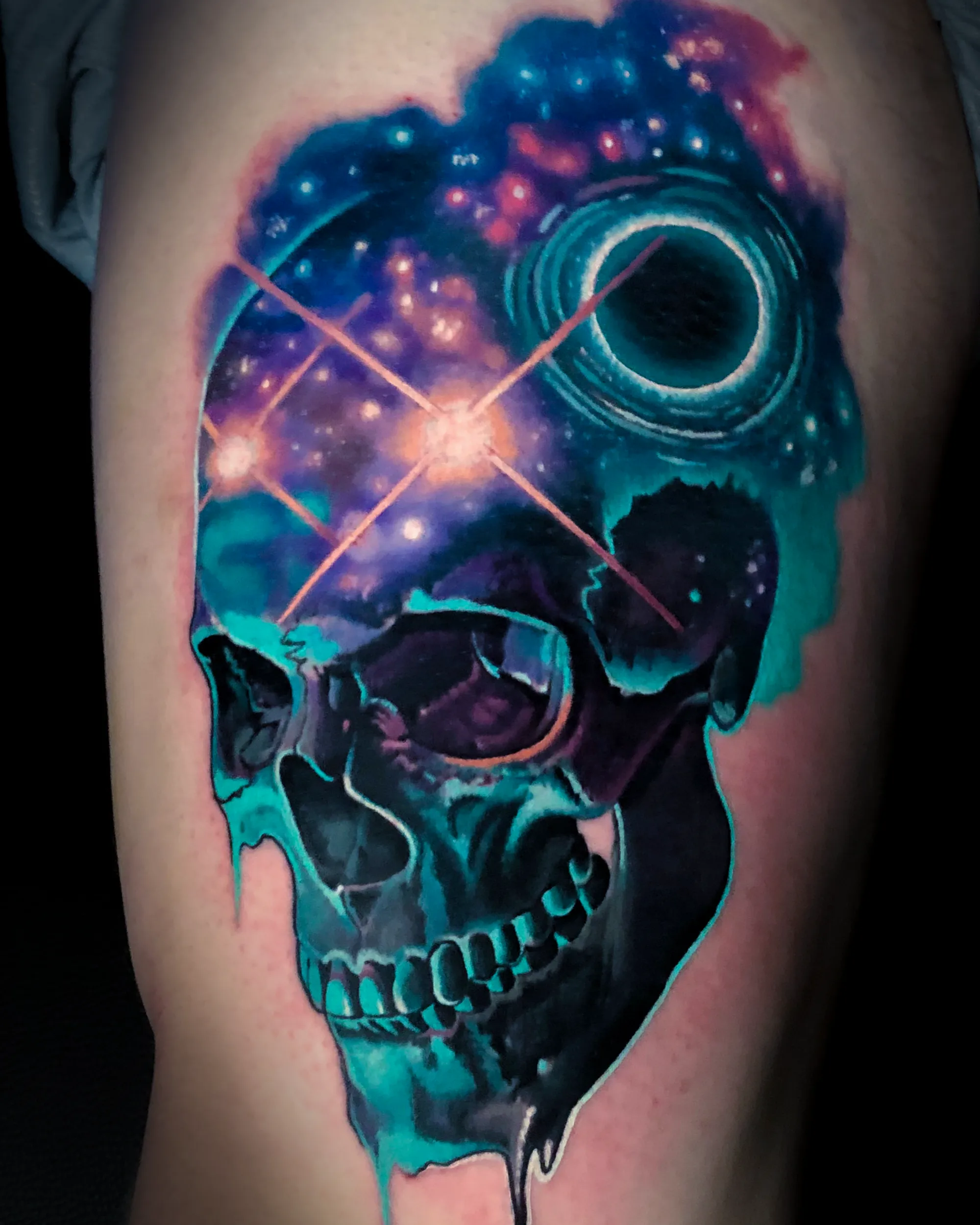 Surreal color galaxy skull with black hole thigh tattoo by Austin tattoo artist Bobby Cupparo