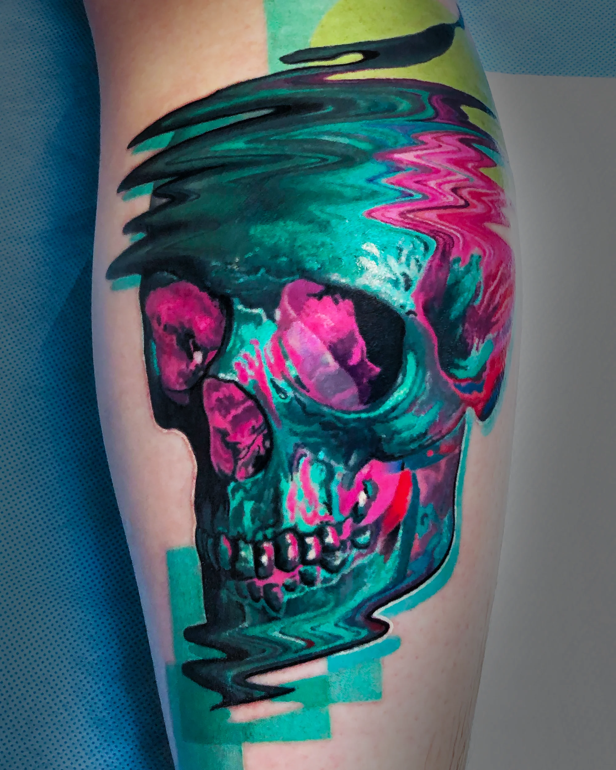 Surreal color glitch skull melting teal pink shin tattoo by Austin tattoo artist Bobby Cupparo