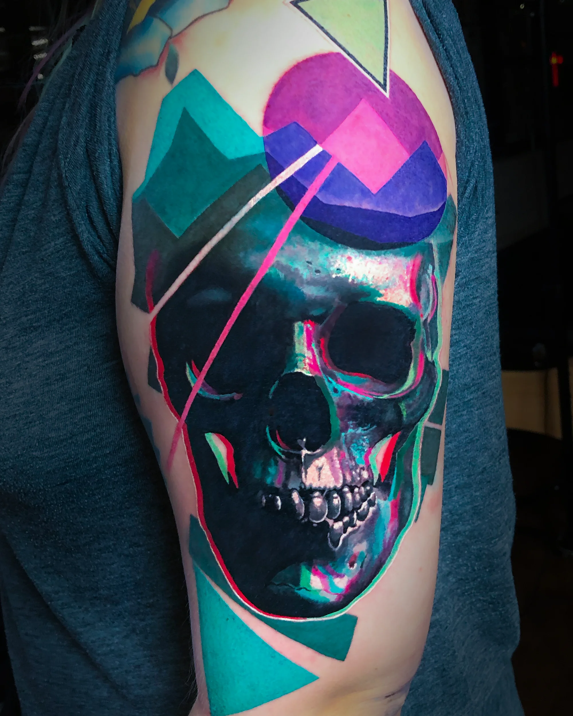Surreal color glitch skull upper arm tattoo by Austin tattoo artist Bobby Cupparo