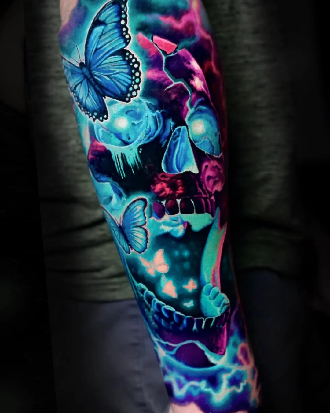 Surreal color neon bioluminescent skull with blue morpho butterflies forearm tattoo by Austin tattoo artist Bobby Cupparo