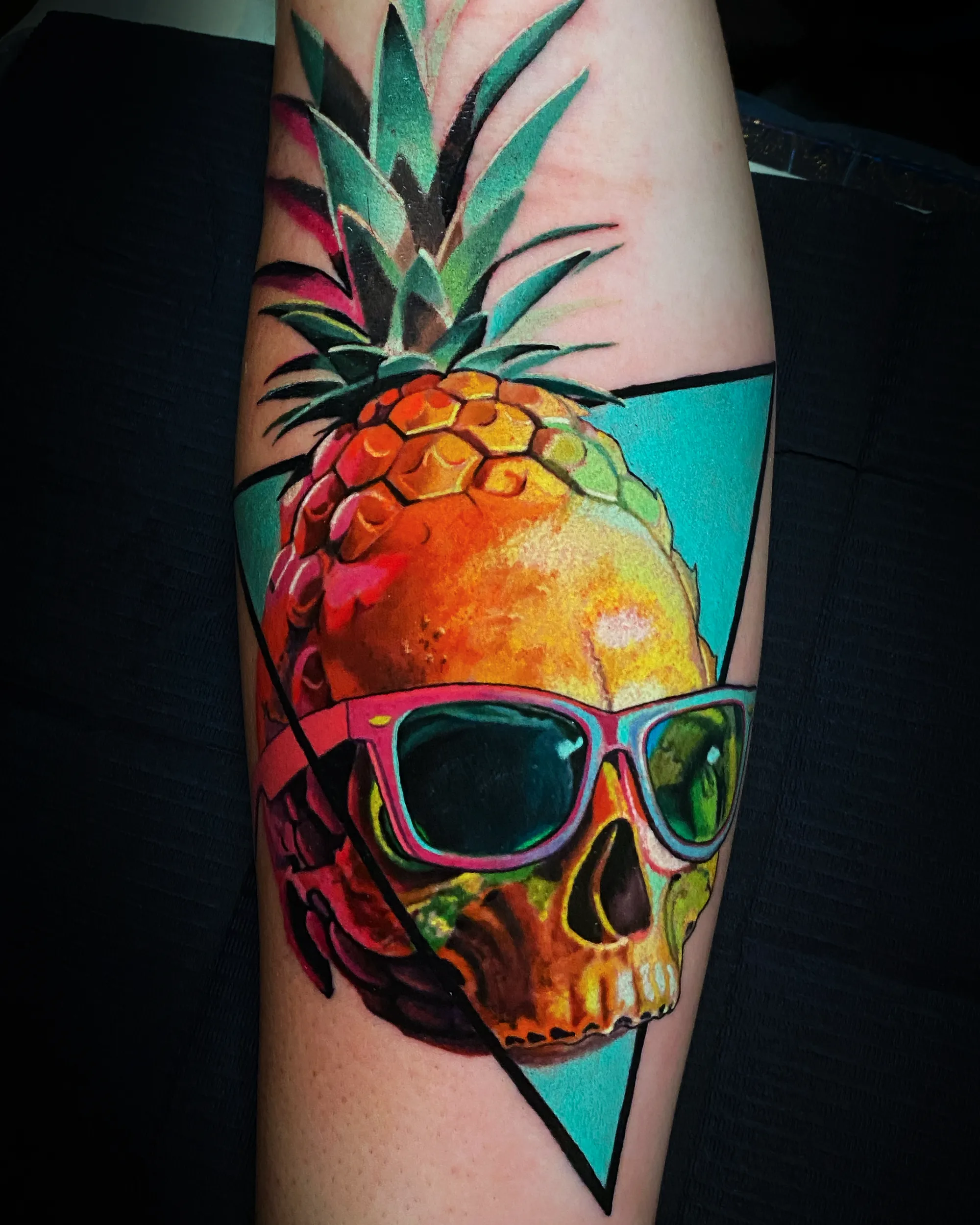 Surreal color pineapple skull with sunglasses forearm tattoo by Austin tattoo artist Bobby Cupparo