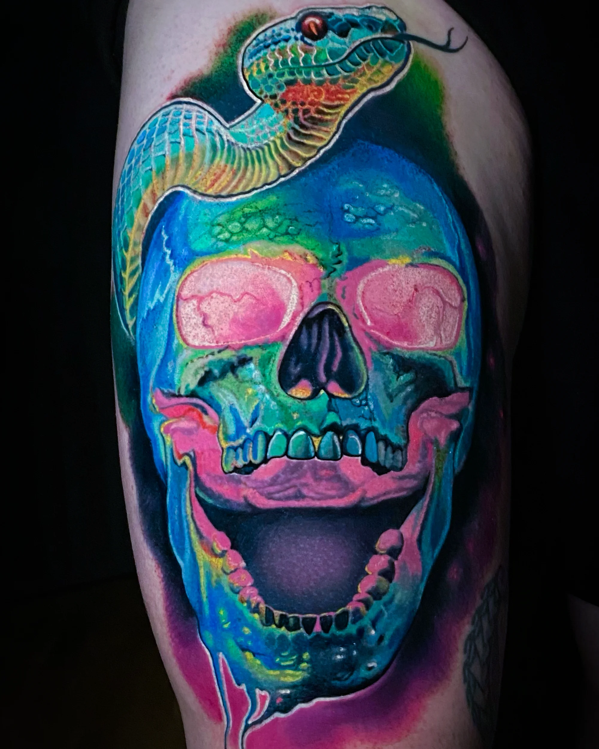 Surreal color skull with cobra snake neon upper arm tattoo by Austin tattoo artist Bobby Cupparo