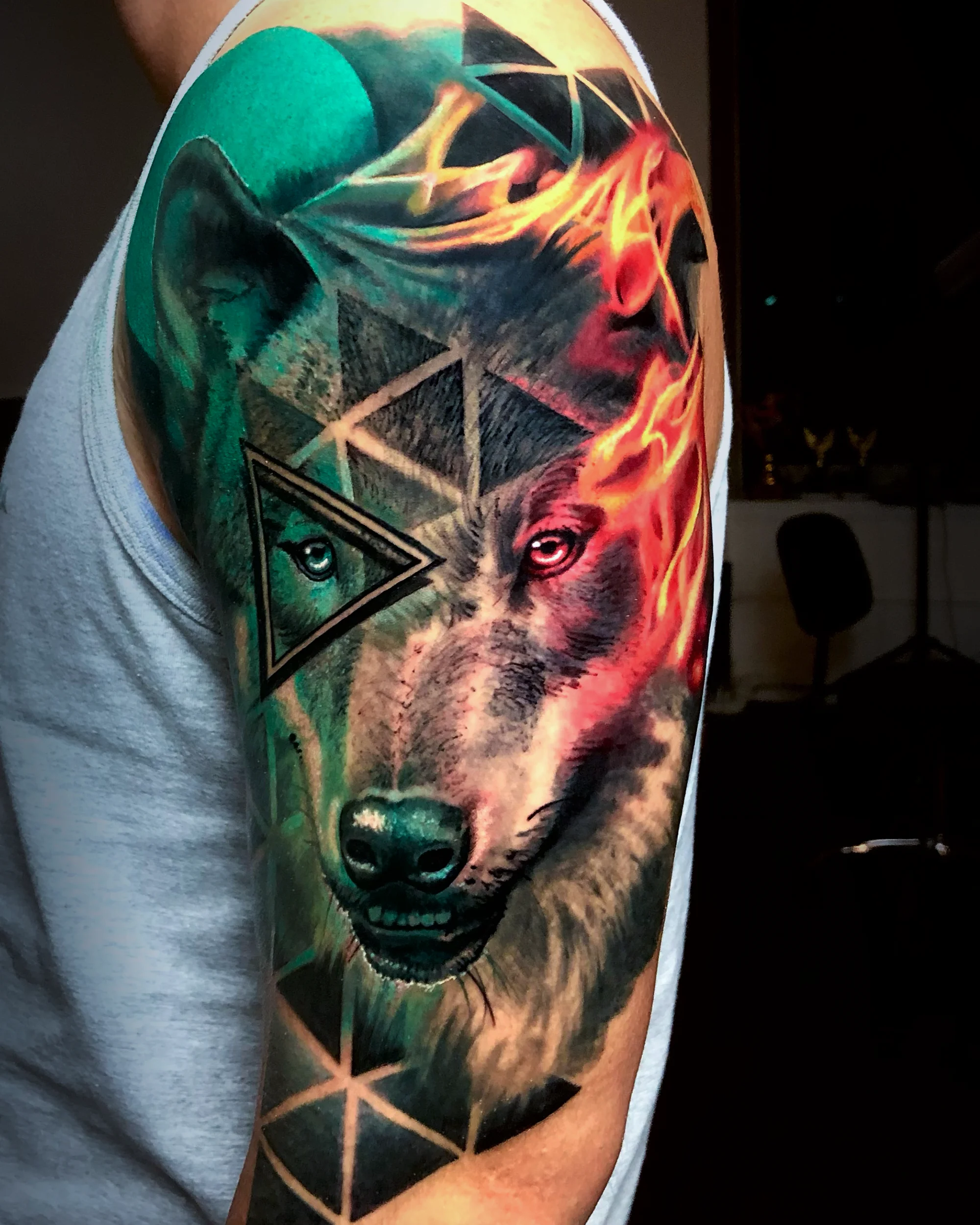 Surreal color wolf fire and ice geometric upper arm tattoo by Austin tattoo artist Bobby Cupparo